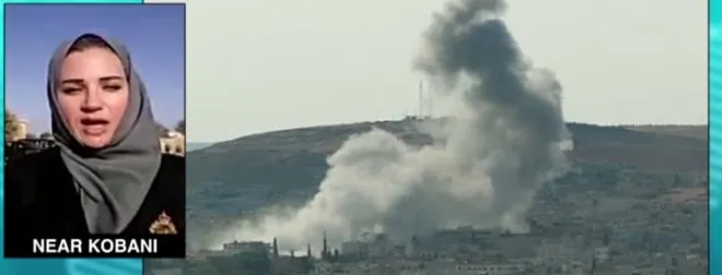A Press TV broadcast frame captioned 'Near Kobani': Serena reporting live in an inset beside footage of smoke rising over the town.