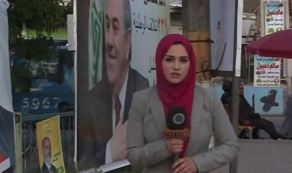 Serena reporting on a Baghdad street lined with election campaign posters, 2014.