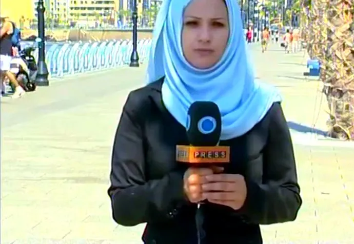 Serena reporting to camera with a Press TV microphone on Beirut's seafront Corniche.