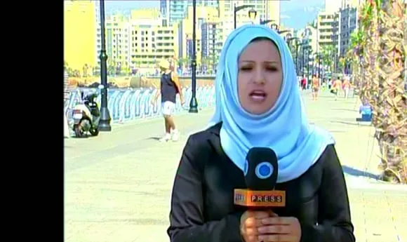 Serena reporting to camera with a Press TV microphone on Beirut's seafront Corniche.